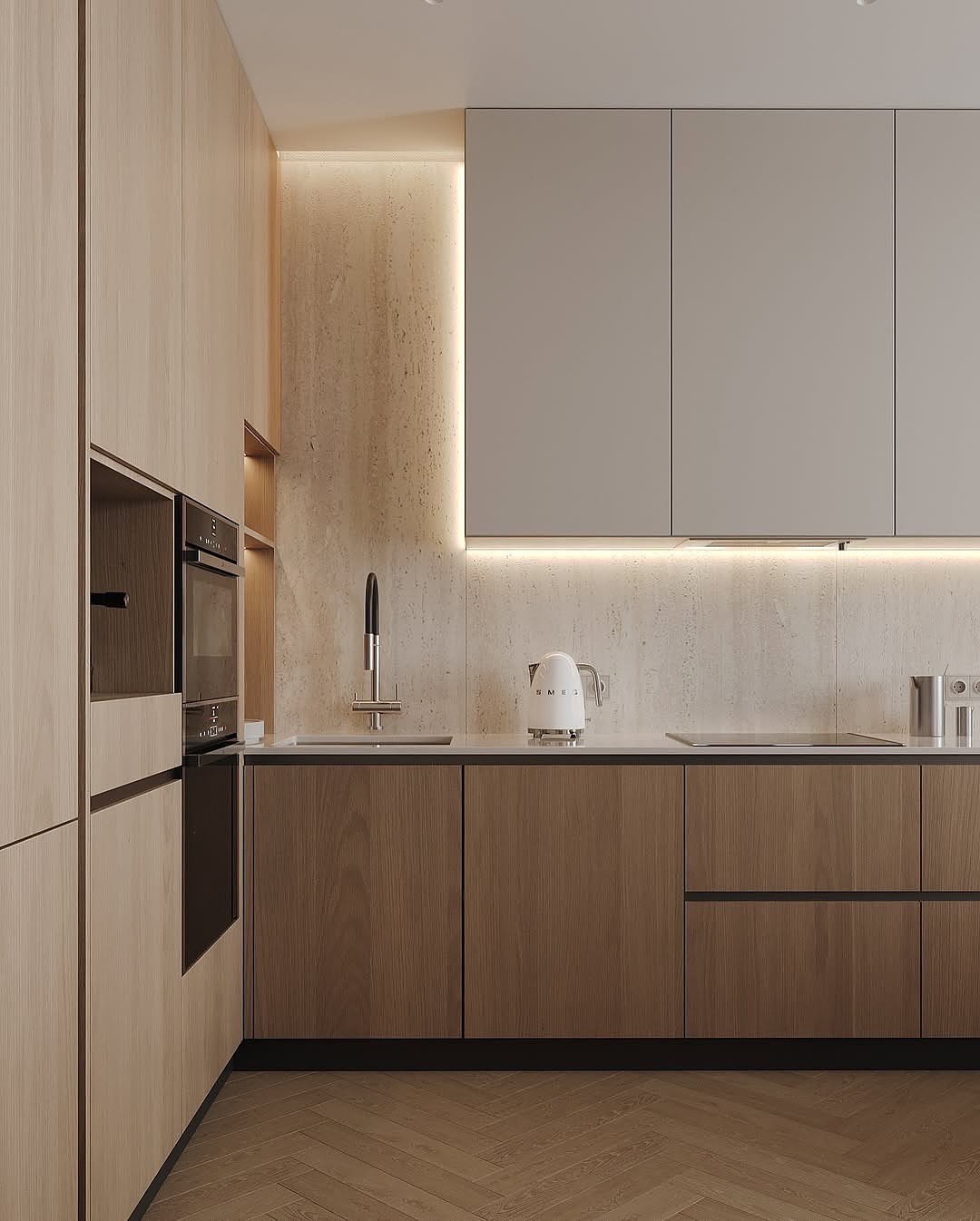 Contemporary L-shaped kitchen with light wood grain cabinets, built-in espresso machine, stacked black ovens, and white quartz countertops with textured beige backsplash. Integrated LED lighting throughout with herringbone wood flooring